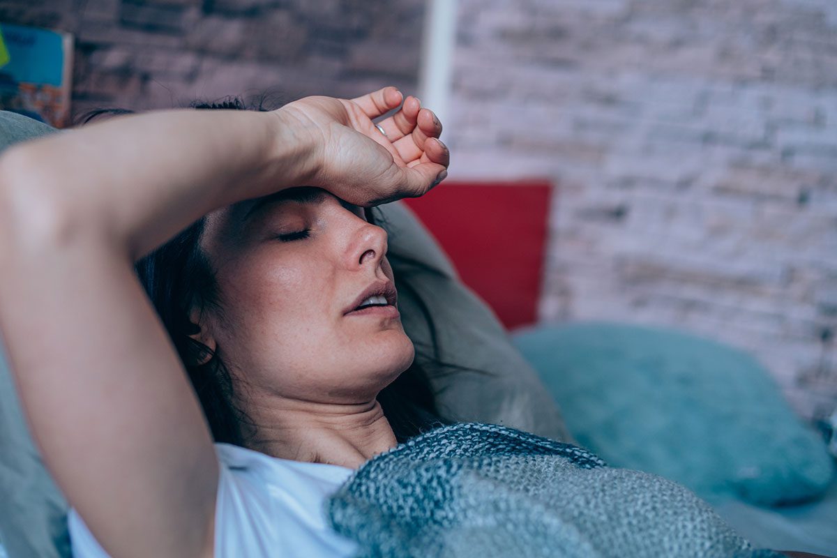 a woman sleeping in bed who is feeling too warm.